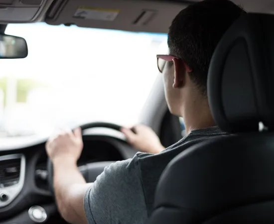 A view from the back seat of a learner's hands on the steering wheel