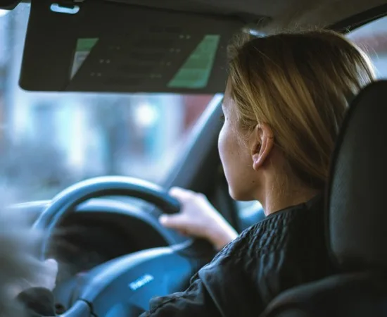 A driver looking ahead at the road with both hands on the wheel